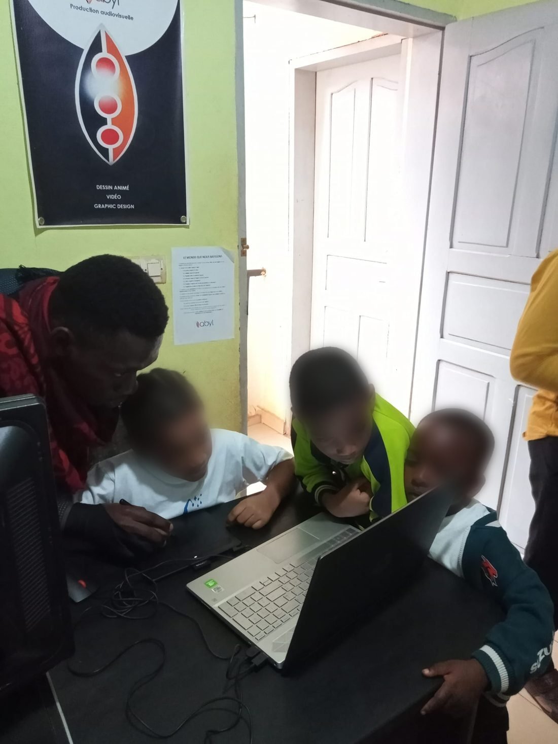 Un enfant travaille sur une tablette graphique à côté d'un ordinateur portable.